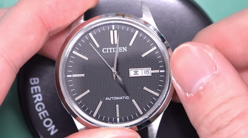 時計のリューズを触っている